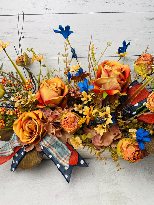 silk floral arrangement in wooden box with orange roses and blue accents and polk dot blue ribbons