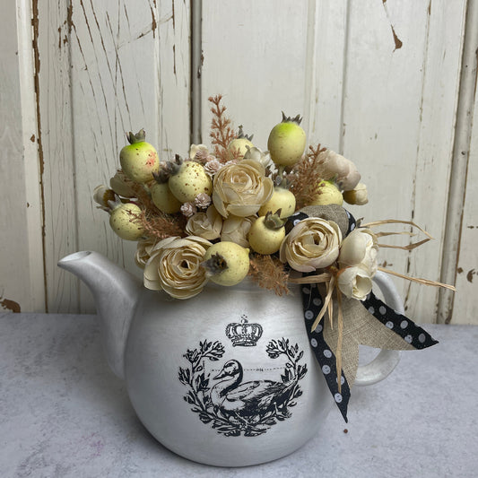 vintage teapot with swan graphic and silk ceam berry and ranunculus silk floral arrangement