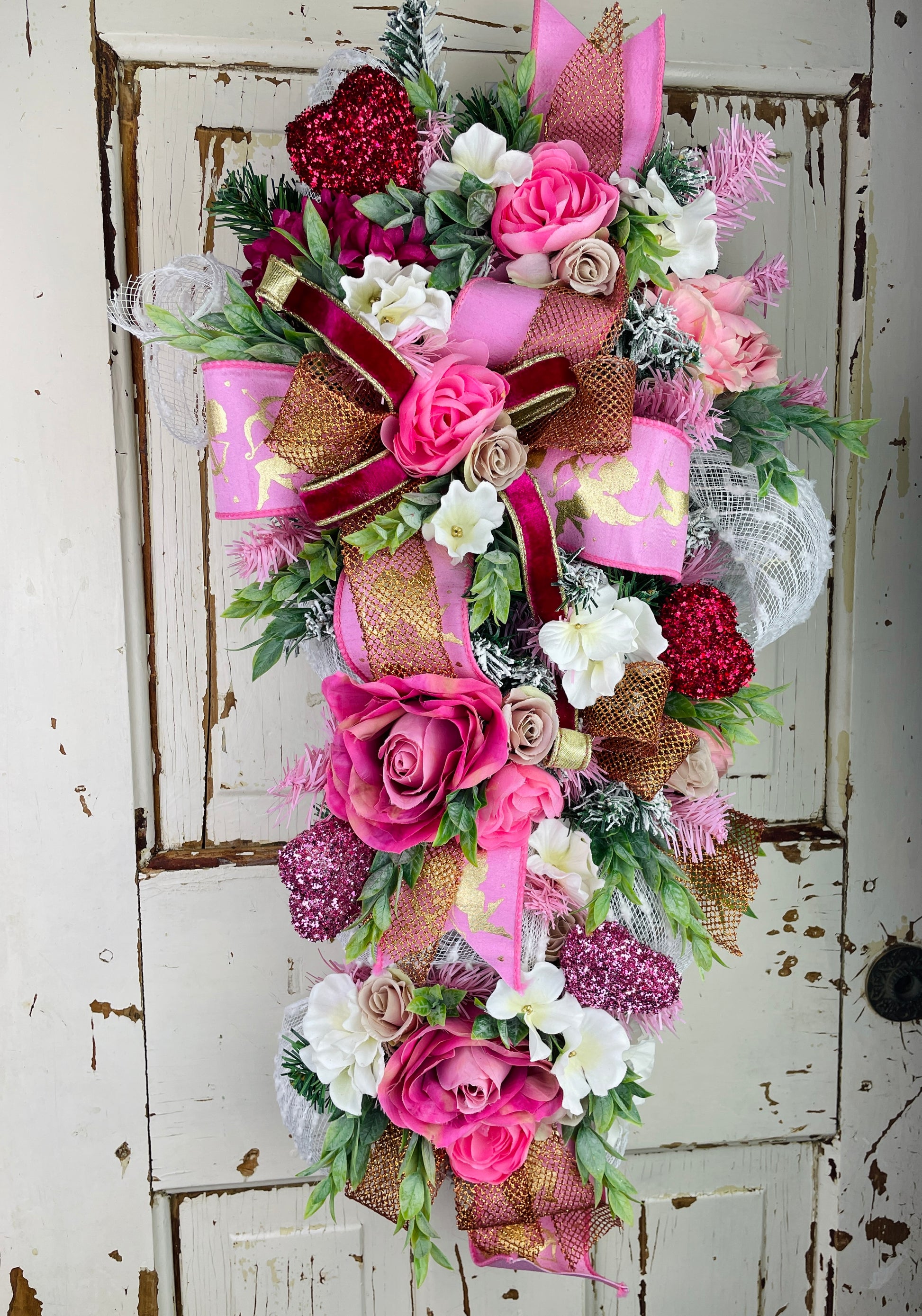 Romantic pink and red Valentine’s wreath with faux roses, glitter hearts, white florals, and layered gold, velvet, and mesh ribbons – handmade heart-themed wall or door decor by Lavender Blue Floral.