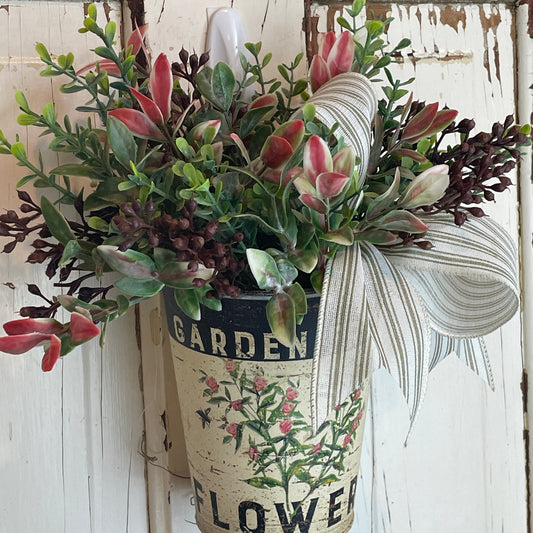 Wall-mounted metal basket filled with faux herbs and greenery in a rustic French country style, perfect for kitchen or patio decor.