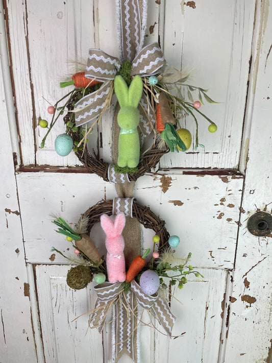 Easter wreath hanger with bunnies and faux colored eggs and a zig zag designer ribbon and faux carrots