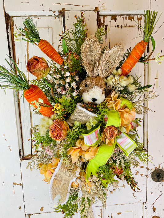 Floral swag with faux carrots and rabbit for interior walls with farmhouse decor and featuring wired striped and burlap ribbons and orange roses