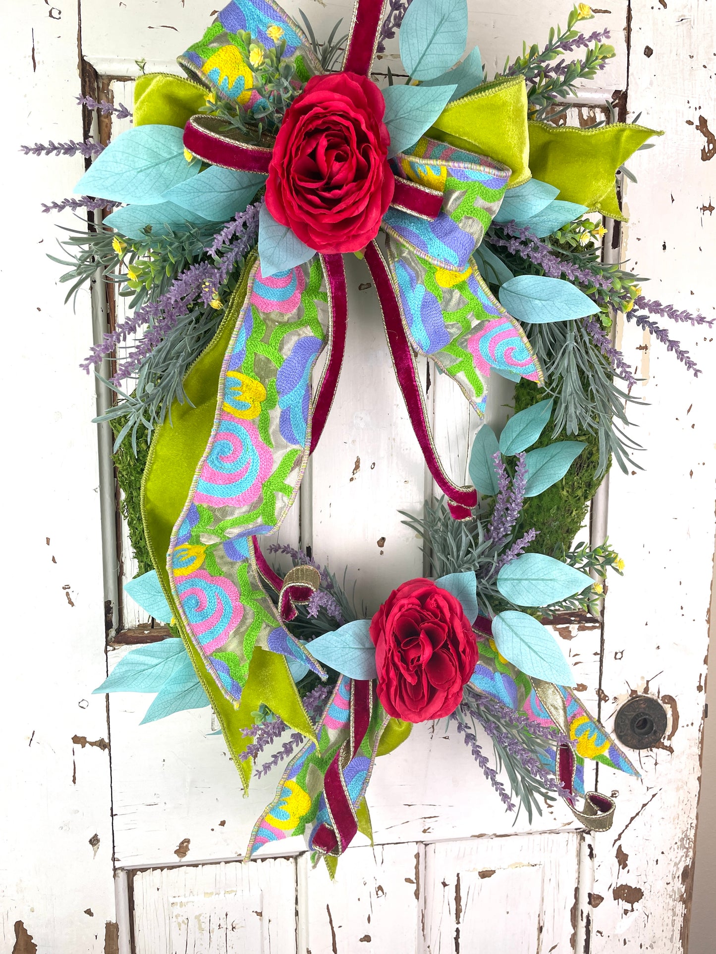 Large oval floral wreath with bright flowers and velvet ribbons