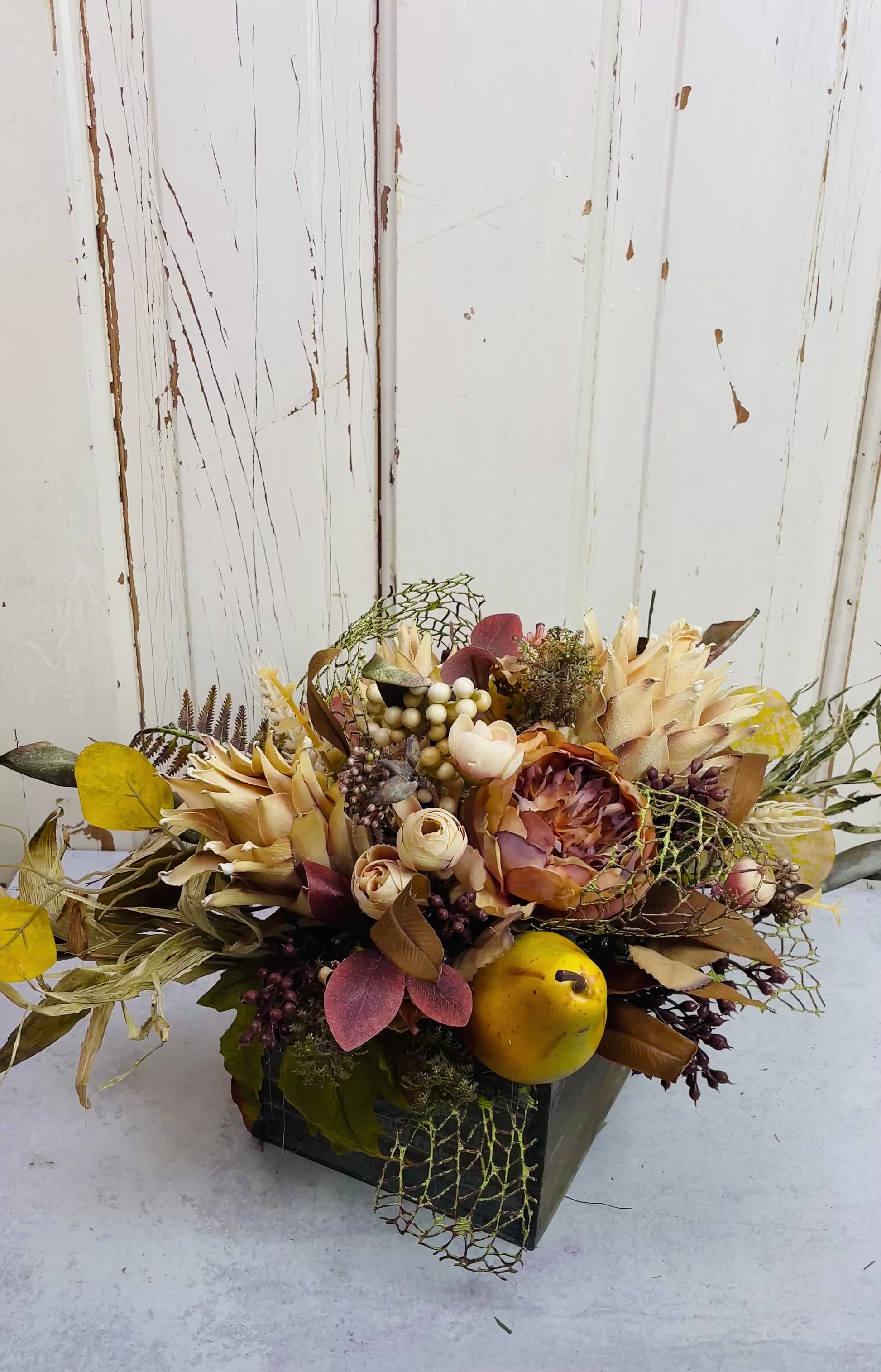 silk floral arrangment in wooden square container with faux protea and pears with warm color roses and eucaoyptus