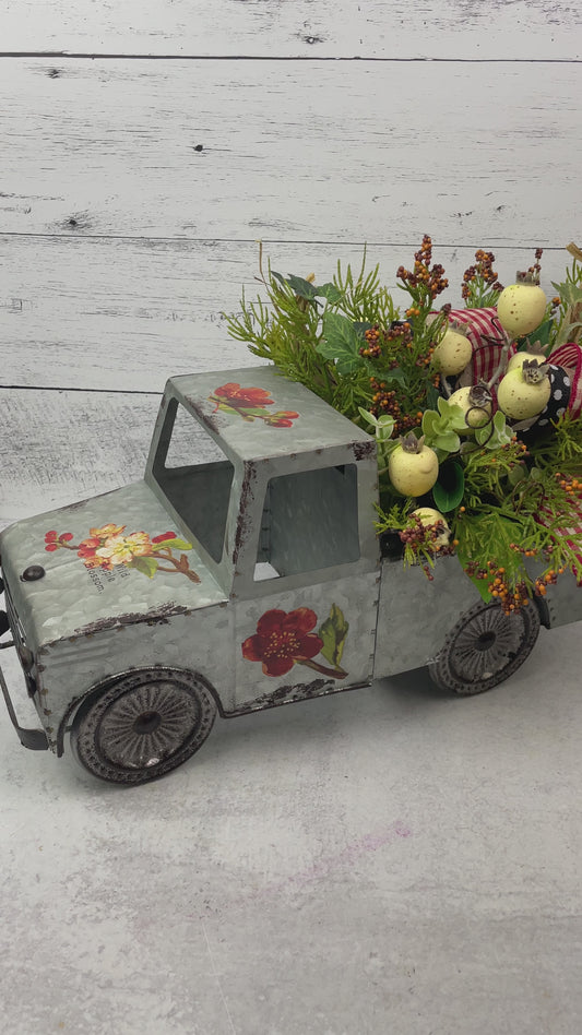 metal vintage looking truck floral container with cream berries , faux evergreen, and red plaid ribbon