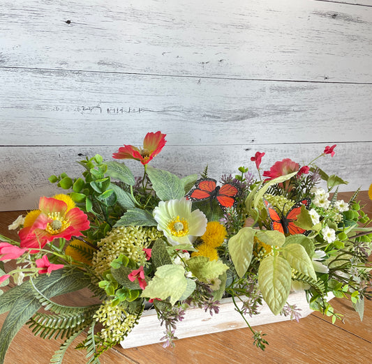 silk floral arrangement with cream and orange poppies and white floral accents, with eucalyptus and orange butterflies